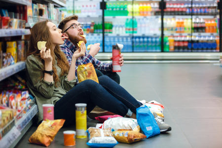 image of couple having potato chips and snacks at a grocery aisle